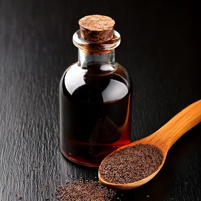 Schwarzkümmelöl mit Holzlöffel voller Schwarzkümmel