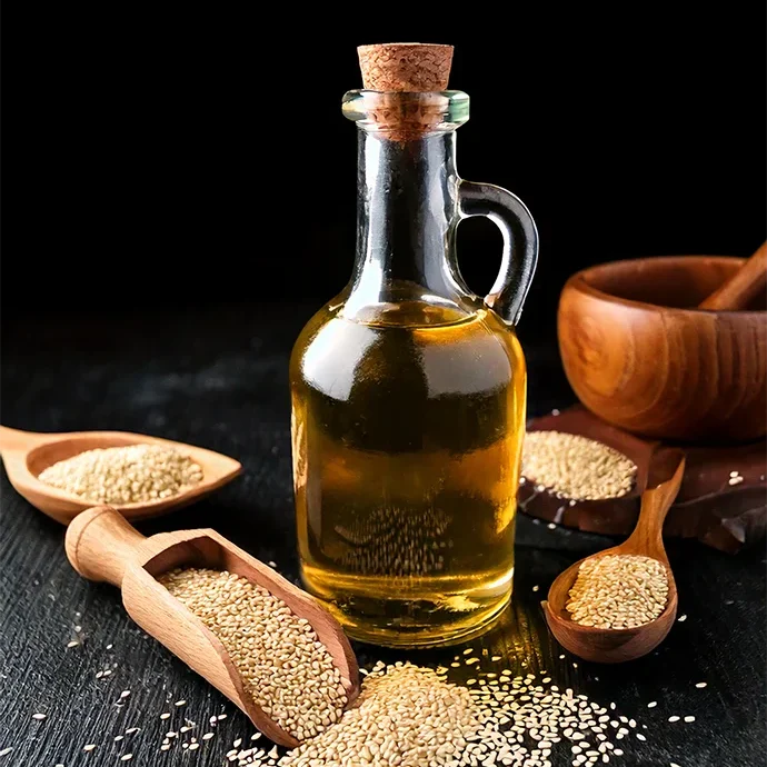 Bottle with sesame oil and wooden spoons with sesame seeds